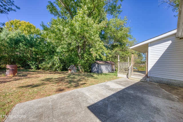 view of yard featuring a patio, a deck, and a shed