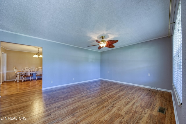 spare room with crown molding, hardwood / wood-style flooring, a textured ceiling, and ceiling fan with notable chandelier