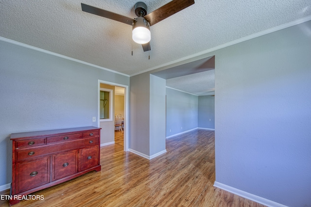 empty room featuring crown molding, a textured ceiling, light hardwood / wood-style floors, and ceiling fan