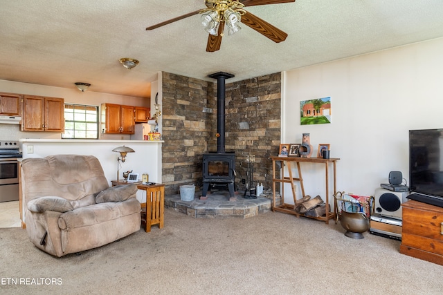 carpeted living room with a wood stove, a textured ceiling, and ceiling fan