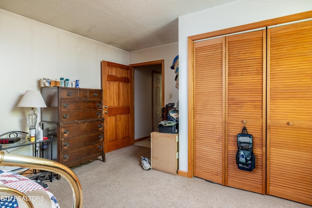 carpeted bedroom featuring a textured ceiling and a closet