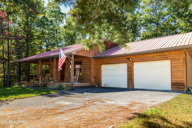 log-style house with covered porch and a garage