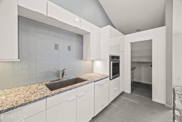 kitchen featuring light stone counters, vaulted ceiling, sink, dishwasher, and oven