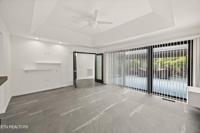 interior space featuring ceiling fan and a tray ceiling