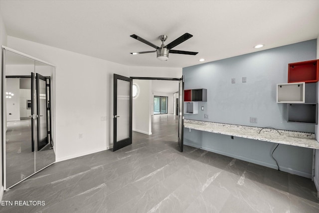 interior space with ceiling fan and light stone countertops