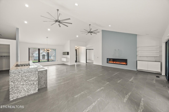 unfurnished living room with ceiling fan with notable chandelier and high vaulted ceiling