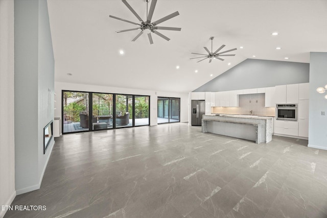 unfurnished living room featuring ceiling fan and high vaulted ceiling