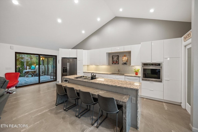 kitchen featuring stainless steel appliances, white cabinetry, sink, and a center island with sink