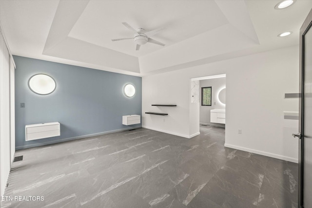 spare room featuring a raised ceiling and ceiling fan