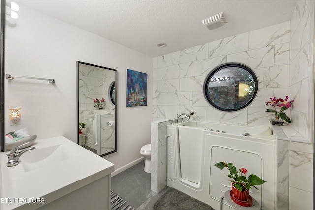 bathroom featuring vanity, toilet, a bath, and a textured ceiling