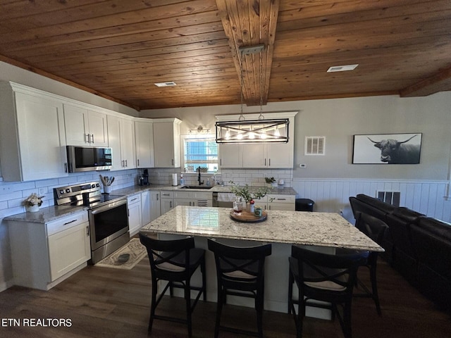 kitchen with white cabinets, stainless steel appliances, dark hardwood / wood-style floors, and hanging light fixtures