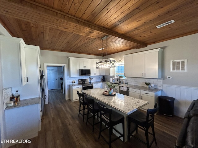 kitchen with dark hardwood / wood-style floors, stainless steel appliances, sink, decorative light fixtures, and white cabinets