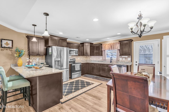 kitchen with decorative light fixtures, kitchen peninsula, appliances with stainless steel finishes, and decorative backsplash