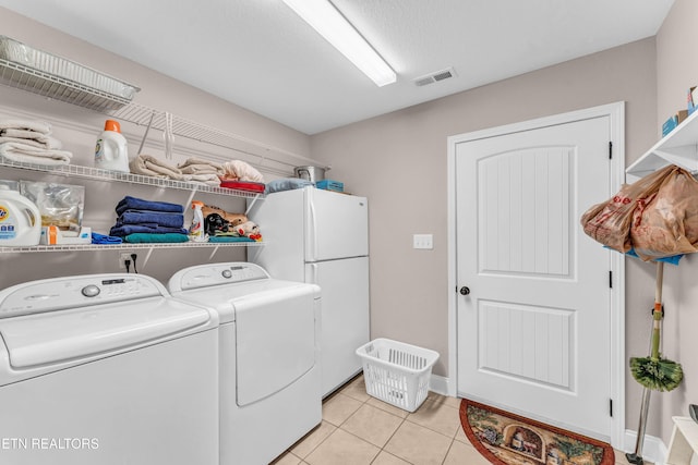 laundry room with a textured ceiling, independent washer and dryer, and light tile patterned floors