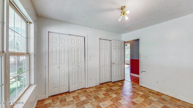 2732 Cherry Fork Rd, Helenwood, TN 37755 - unfurnished bedroom featuring a textured ceiling, multiple windows, and multiple closets