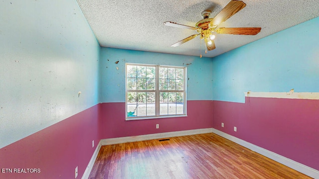 empty room with ceiling fan, hardwood / wood-style flooring, and a textured ceiling