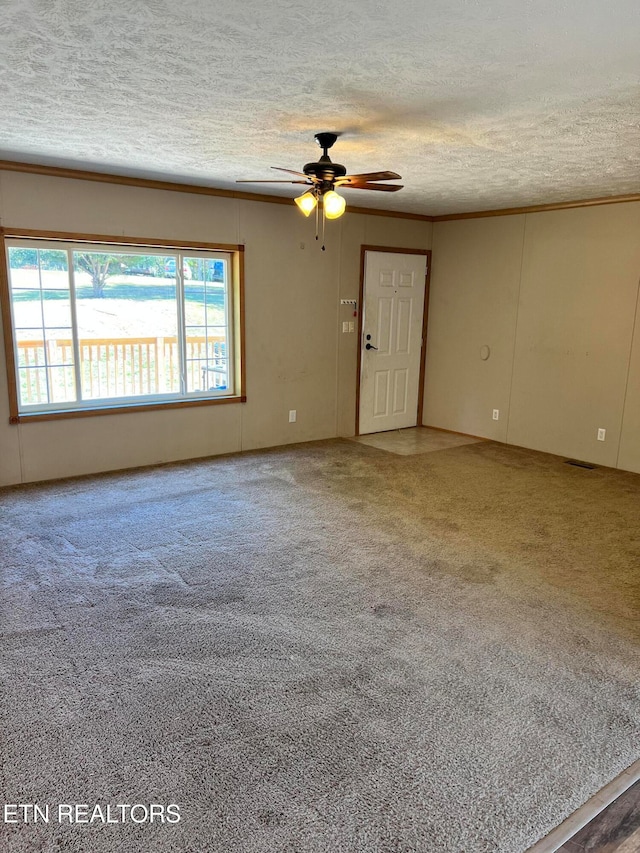 carpeted spare room featuring ornamental molding, a textured ceiling, and ceiling fan