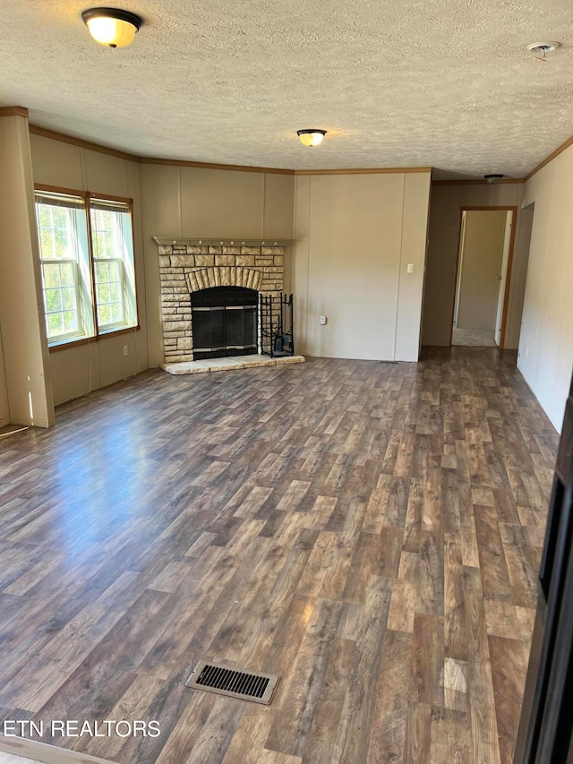 unfurnished living room featuring a textured ceiling, a stone fireplace, and dark hardwood / wood-style floors