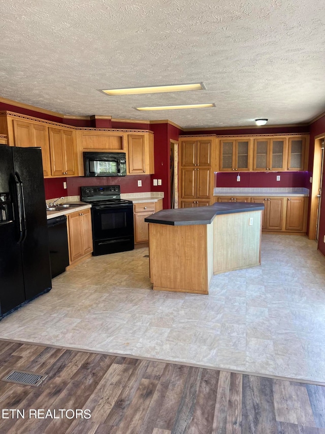 kitchen featuring black appliances, light hardwood / wood-style flooring, a textured ceiling, and a center island