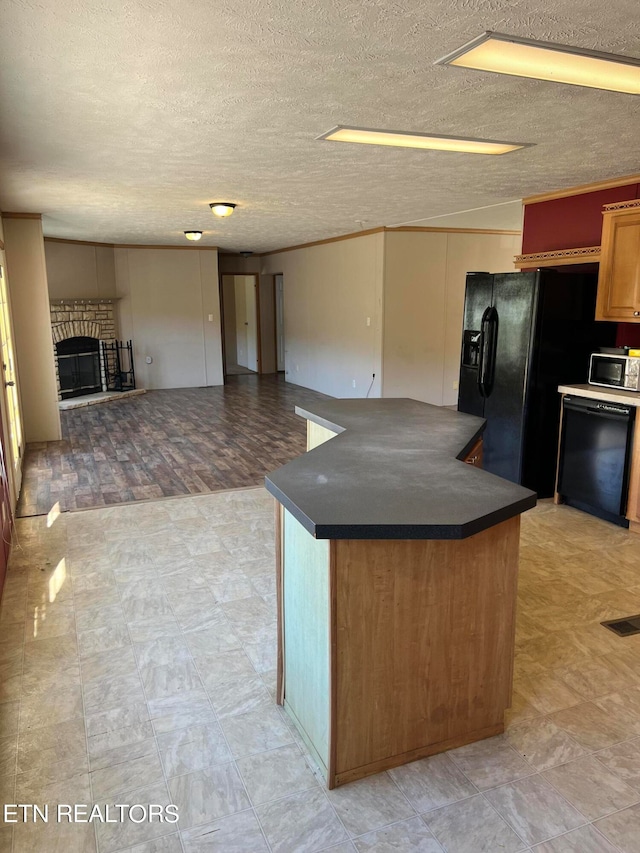 kitchen featuring light hardwood / wood-style floors, a textured ceiling, black dishwasher, and a brick fireplace