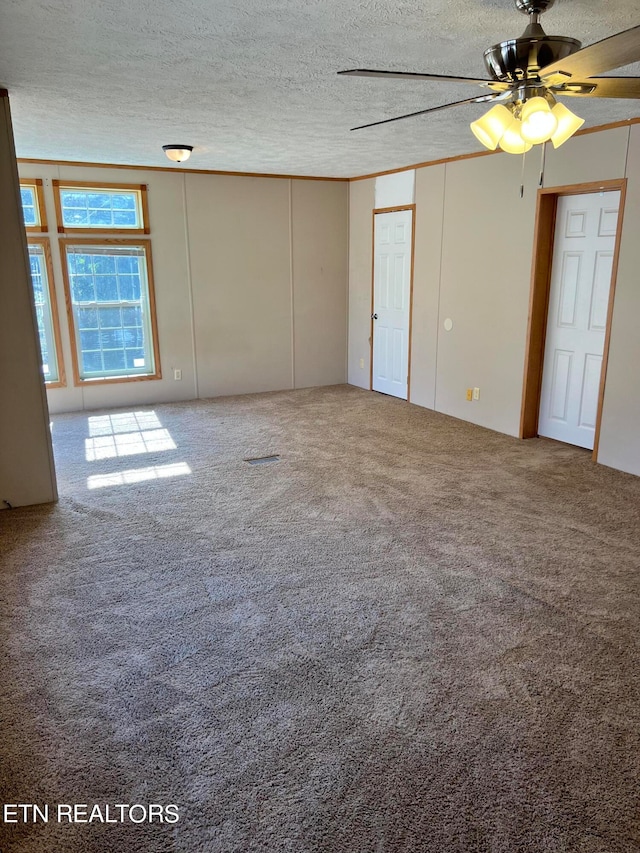 empty room featuring a textured ceiling, carpet flooring, and ceiling fan