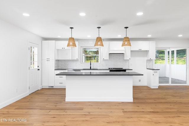 kitchen featuring a kitchen island, light hardwood / wood-style flooring, hanging light fixtures, sink, and white cabinets