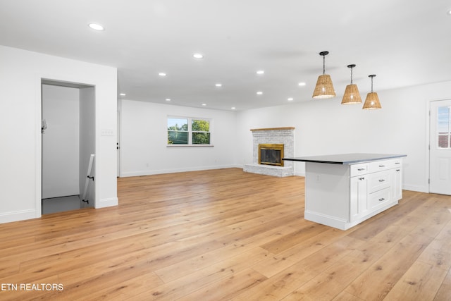 kitchen with white cabinetry, hanging light fixtures, light wood-type flooring, and a kitchen island