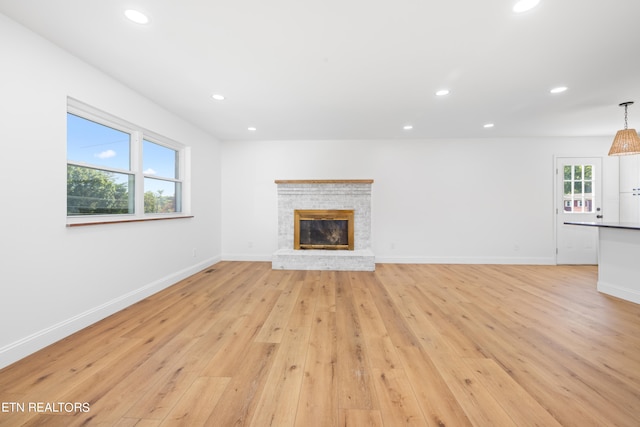 unfurnished living room featuring a fireplace and light hardwood / wood-style floors