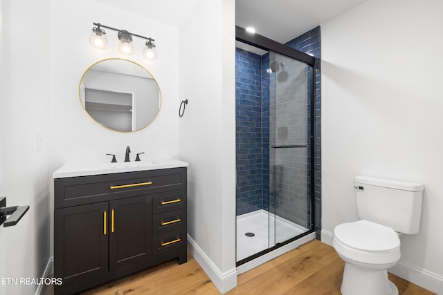 bathroom featuring vanity, hardwood / wood-style floors, a shower with shower door, and toilet