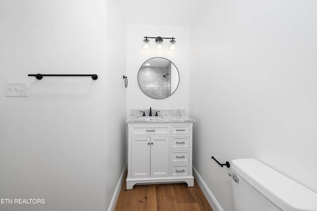 bathroom with toilet, hardwood / wood-style flooring, and vanity