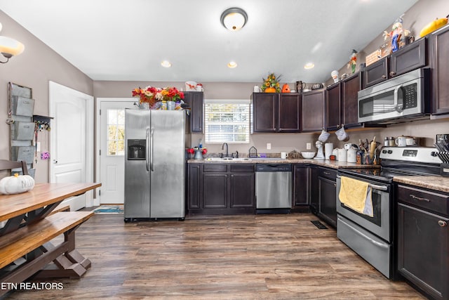 kitchen with dark hardwood / wood-style floors, stone countertops, sink, dark brown cabinetry, and stainless steel appliances