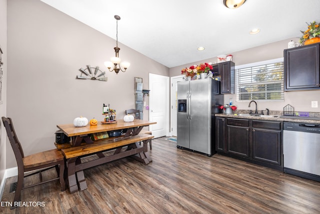 kitchen featuring dark wood-type flooring, hanging light fixtures, sink, vaulted ceiling, and appliances with stainless steel finishes