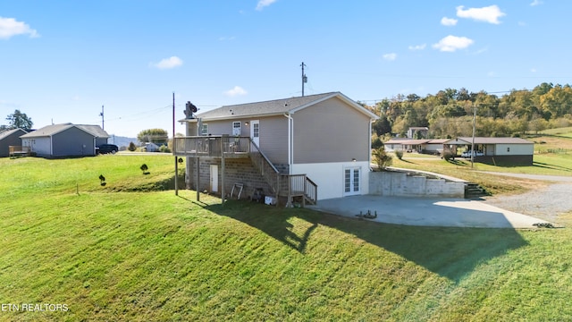 rear view of property featuring a wooden deck, a patio, and a lawn