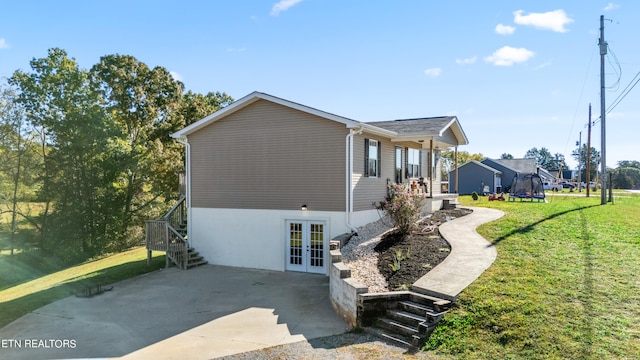 view of home's exterior featuring french doors, a yard, and a trampoline