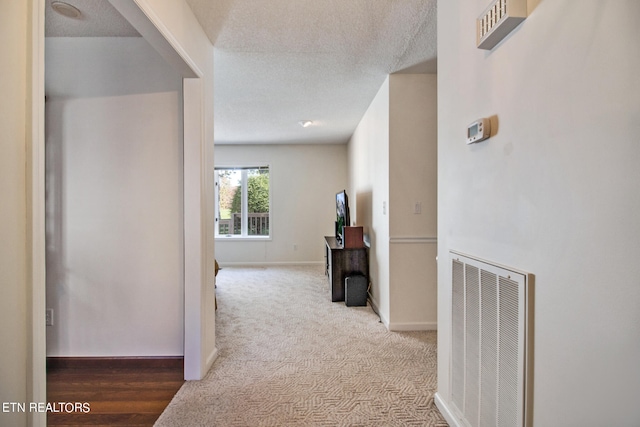 hallway with carpet flooring and a textured ceiling