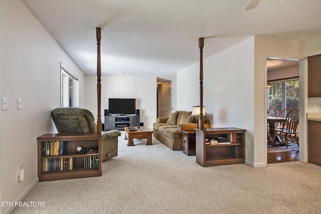 living room with a textured ceiling, carpet floors, and ceiling fan