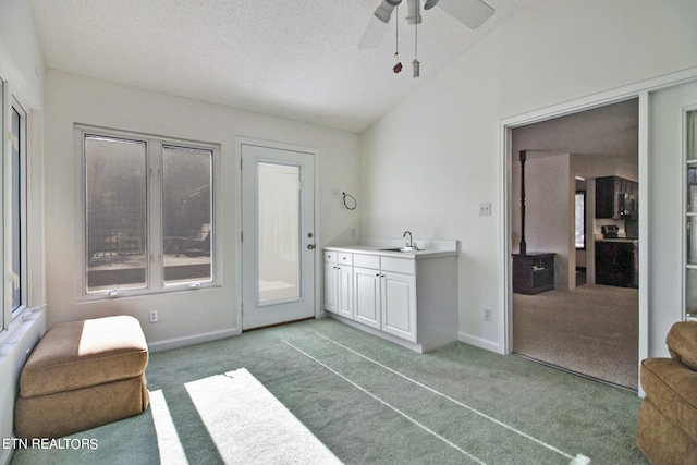 interior space featuring lofted ceiling, ceiling fan, a textured ceiling, sink, and light colored carpet