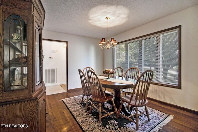 dining area featuring dark wood-type flooring, a textured ceiling, and an inviting chandelier