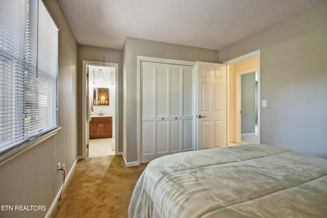 carpeted bedroom with a closet, a textured ceiling, and ensuite bathroom