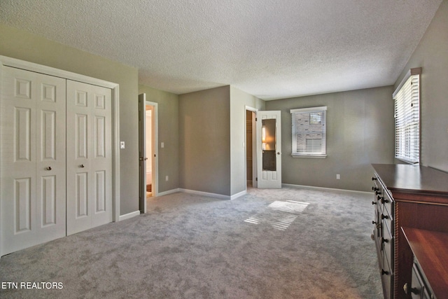 unfurnished bedroom featuring light carpet, a closet, and a textured ceiling