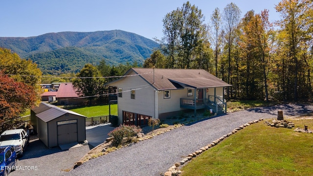 exterior space with an outdoor structure, a carport, a mountain view, and a front lawn