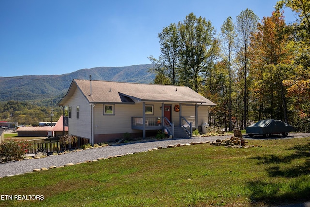 view of front of home featuring covered porch, a mountain view, and a front lawn