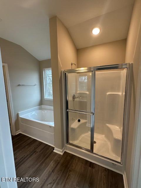 full bath with a garden tub, wood finished floors, baseboards, vaulted ceiling, and a shower stall