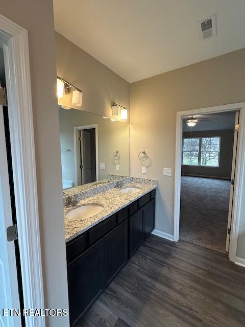 full bathroom with double vanity, visible vents, a sink, and wood finished floors