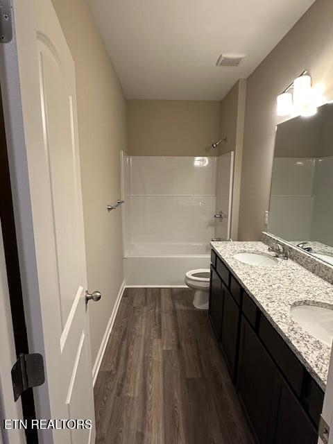 full bathroom with toilet, visible vents, a sink, and wood finished floors