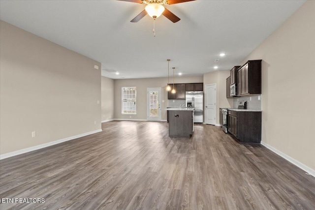 unfurnished living room featuring a ceiling fan, baseboards, and dark wood-style flooring