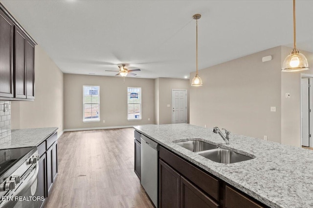 kitchen with dark brown cabinetry, stainless steel appliances, light wood-type flooring, pendant lighting, and a sink