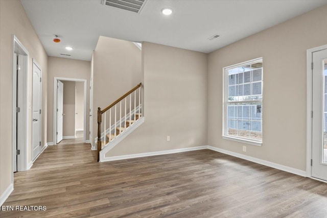 entrance foyer featuring visible vents, stairway, baseboards, and wood finished floors