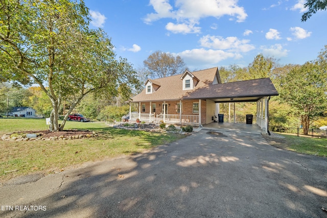 view of front facade with brick siding, covered porch, a front yard, a carport, and driveway