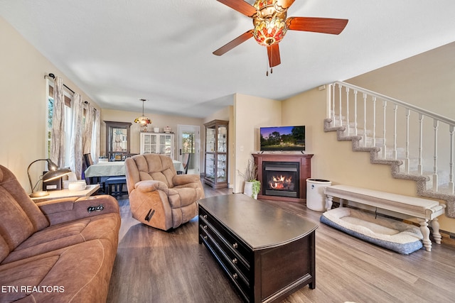 living area featuring ceiling fan, a lit fireplace, and light wood-style flooring